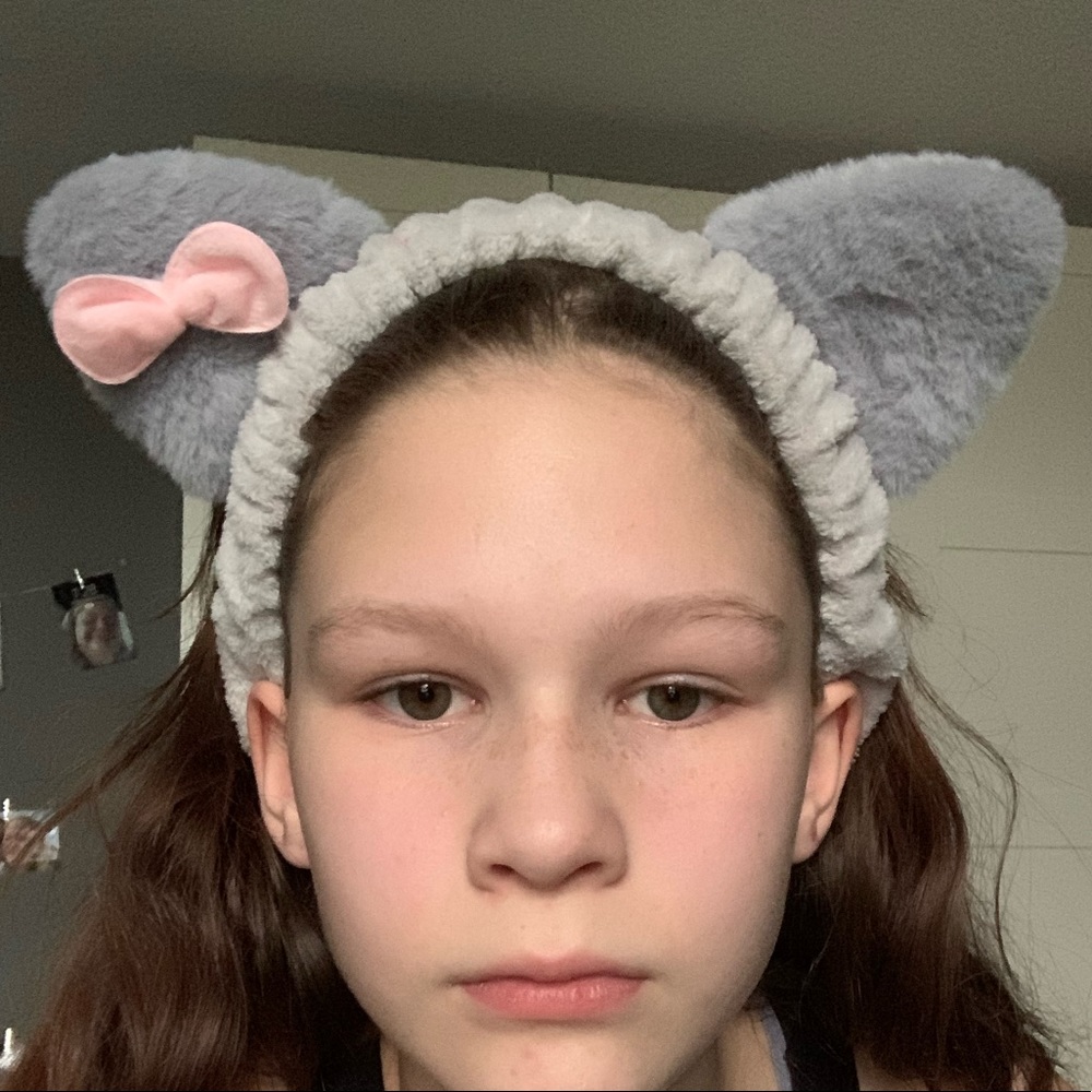 This is a headband that is a cat with a bow on it, it’s grey and fluffy.